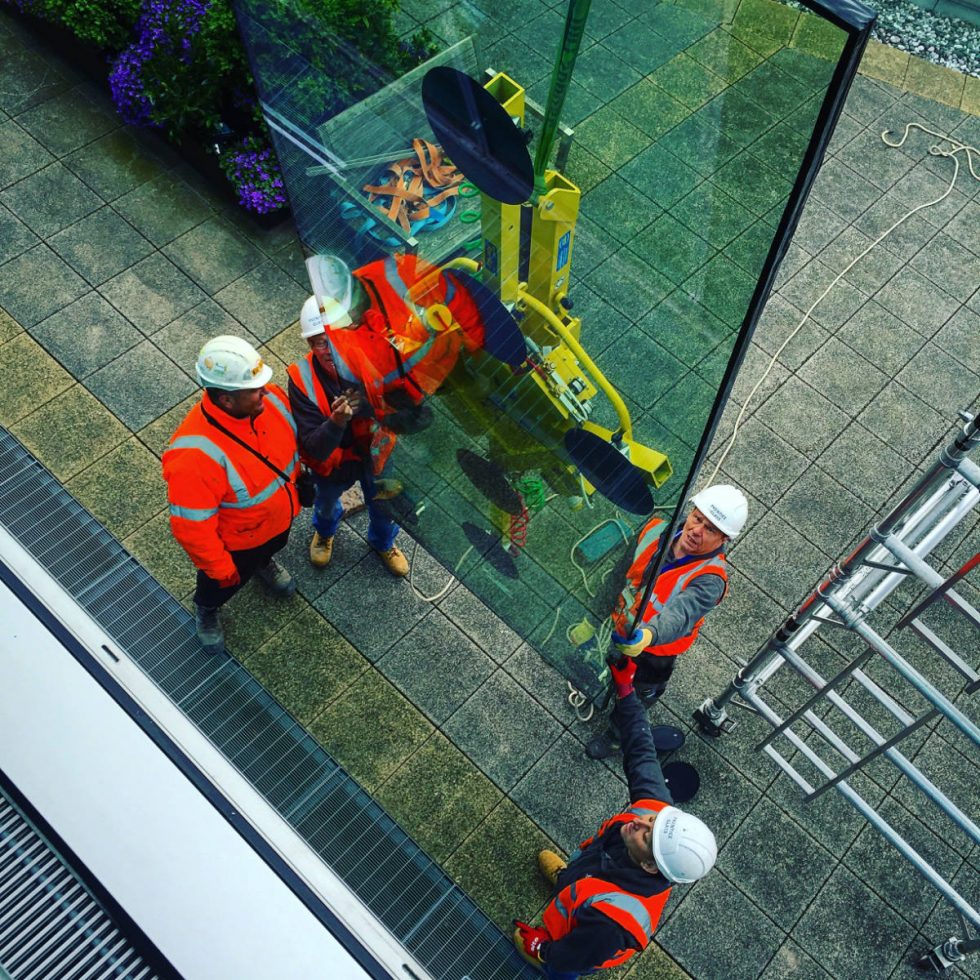 4 people directing a glass pane machine
