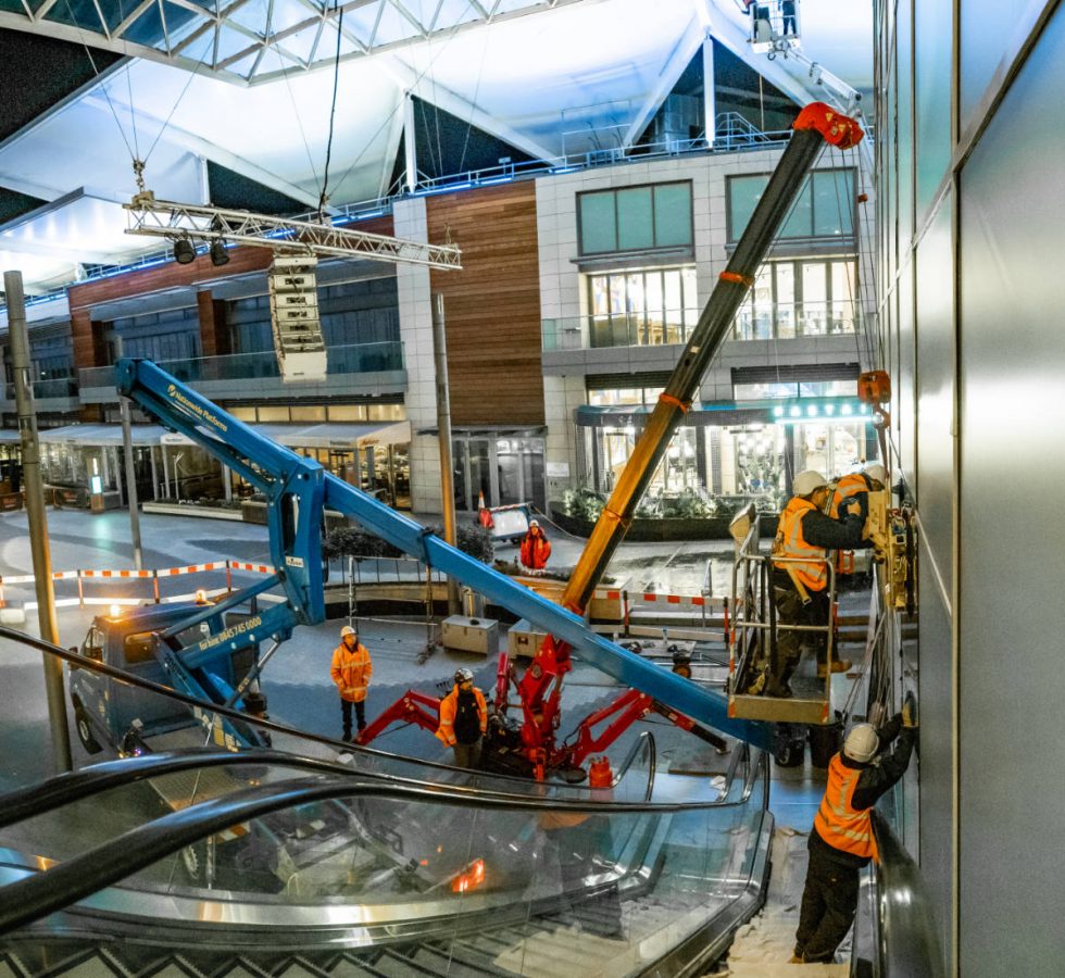 people installing glass next to escalator